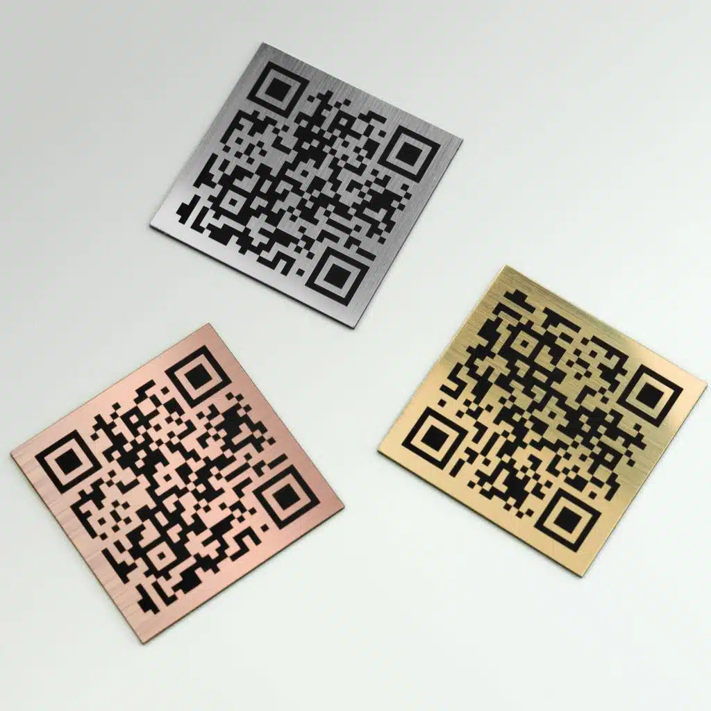 Three metallic QR code plates on a white background: one silver, one bronze, and one gold, all with brushed finishes.