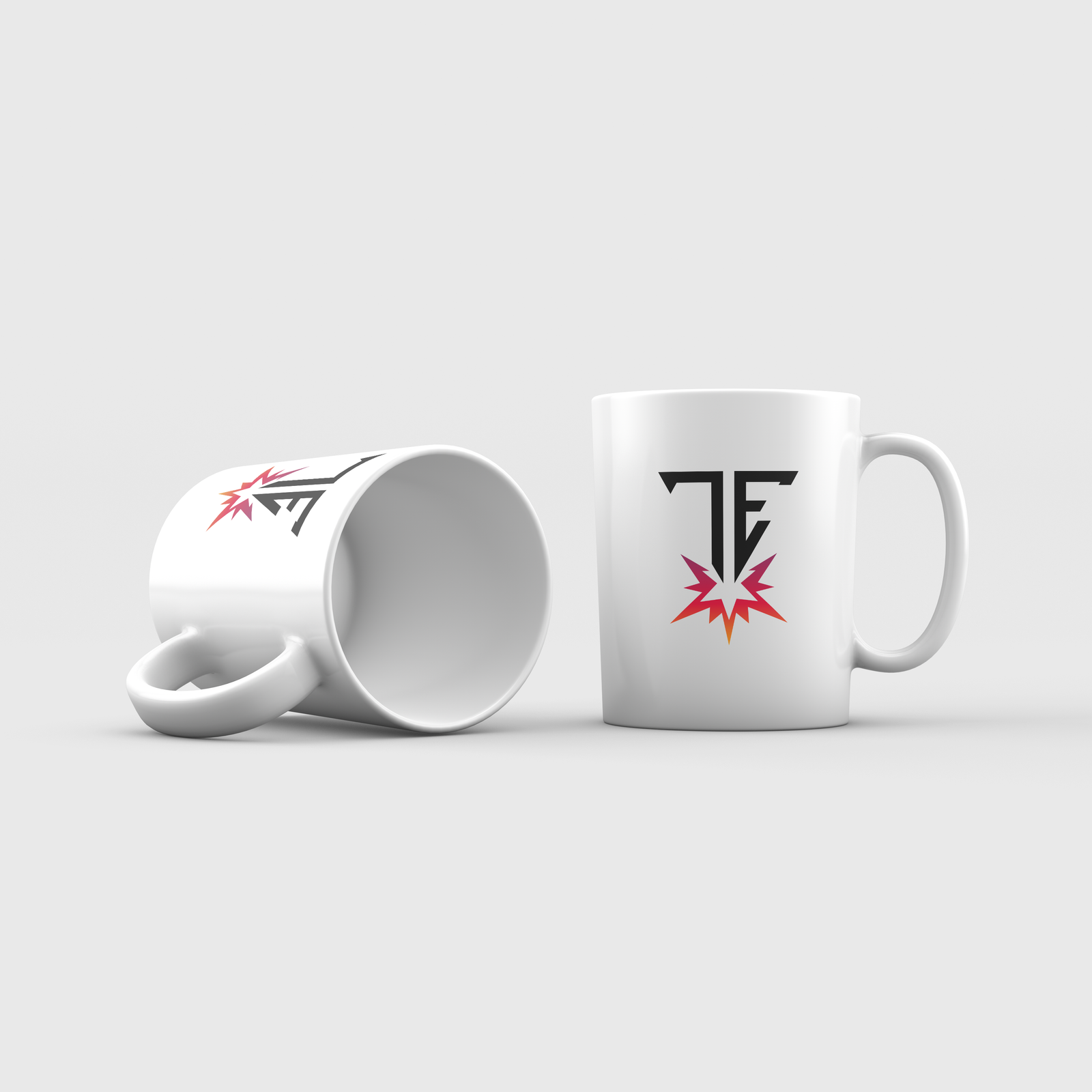 Two white ceramic coffee mugs against a light grey background. One stands upright, the other lies sideways, both display a black 'TF' or 'TE' logo above a red-orange gradient burst graphic.