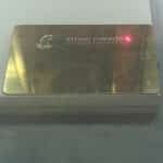 Scratched gold membership card for "Arrow Meadow Exclusive Fisheries" with a fish logo and red laser dot, indicating a marking process.