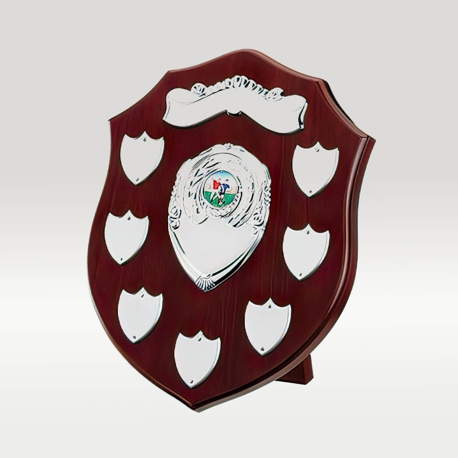 A classic dark wooden award shield with eight small silver engraving plaques and a large central silver emblem featuring a sports scene.