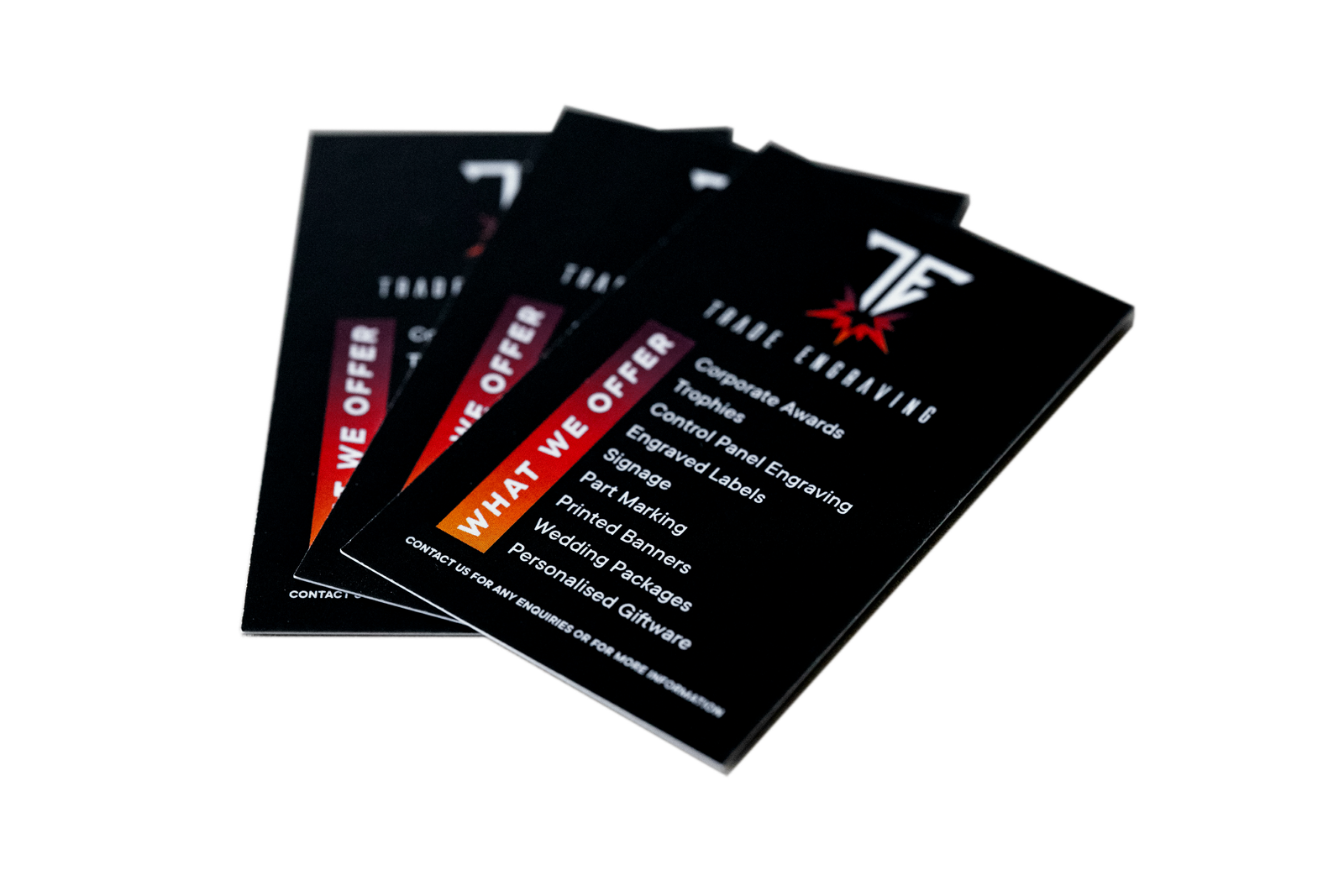 Stack of black Trade Engraving business cards or flyers displaying a list of services like corporate awards, trophies, and engraved labels.